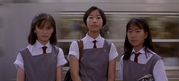 Movie still from “Baraka” (1992), directed by Ron Fricke – A group of young women standing next to each other in front of a train; Medium shot, Low angle