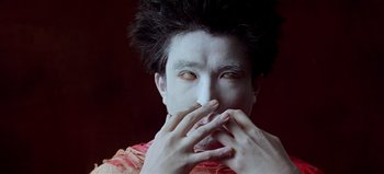 Movie still from “Baraka” (1992), directed by Ron Fricke – A man with his hands over his mouth; Close Up shot, Low angle