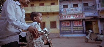 Movie still from “Baraka” (1992), directed by Ron Fricke – A young boy riding on the back of a motorcycle; Medium shot, Low angle