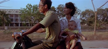 Movie still from “Baraka” (1992), directed by Ron Fricke – A man and a woman and a baby on a motorcycle; Medium shot, Low angle