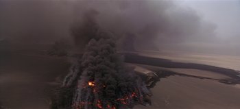 Movie still from “Baraka” (1992), directed by Ron Fricke – An aerial view of a fire burning on a beach; Extreme Wide shot, High angle