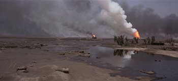 Movie still from “Baraka” (1992), directed by Ron Fricke – An oil rig is burning in the middle of a field; Extreme Wide shot, High angle