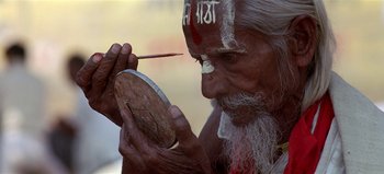 Movie still from “Baraka” (1992), directed by Ron Fricke – An old man is holding a paintbrush in his mouth; Extreme Close Up shot, Overhead angle
