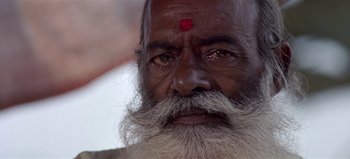 Movie still from “Baraka” (1992), directed by Ron Fricke – An old man with a beard and a red forehead; Extreme Close Up shot, Low angle