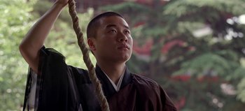 Movie still from “Baraka” (1992), directed by Ron Fricke – A man in a black and white robe looking up; Close Up shot, Low angle