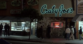 Movie still from “Barfly” (1987), directed by Barbet Schroeder – Two people walking down the sidewalk in front of crabby joe's; Extreme Wide shot, Low angle
