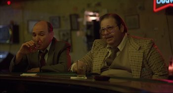 Movie still from “Barfly” (1987), directed by Barbet Schroeder – Two men sitting at a table in front of each other; Medium shot, Low angle