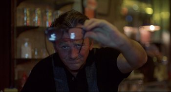 Movie still from “Barfly” (1987), directed by Barbet Schroeder – A man holding a pair of glasses in front of his face; Close Up shot, Low angle