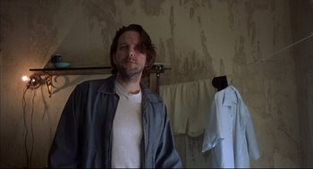 Movie still from “Barfly” (1987), directed by Barbet Schroeder – A man standing in front of a dirty wall in a room; Close Up shot, Low angle