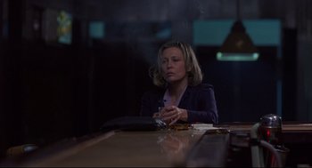 Movie still from “Barfly” (1987), directed by Barbet Schroeder – A woman sitting at a table in a dimly - lit room; Medium shot, Over the shoulder angle