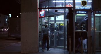 Movie still from “Barfly” (1987), directed by Barbet Schroeder – A man walking into a store with a bud light sign on the door; Wide shot, Low angle