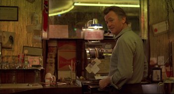 Movie still from “Barfly” (1987), directed by Barbet Schroeder – A man standing at a counter in front of an old jukebox; Medium shot, Over the shoulder angle