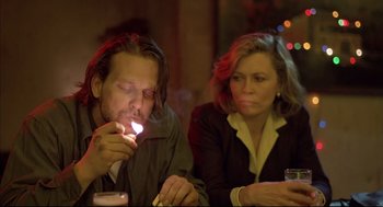 Movie still from “Barfly” (1987), directed by Barbet Schroeder – A man and a woman sitting at a table with a cigarette in their mouth; Close Up shot, Low angle