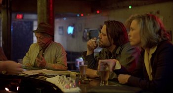 Movie still from “Barfly” (1987), directed by Barbet Schroeder – A group of people sitting at a table drinking; Medium shot, Over the shoulder angle