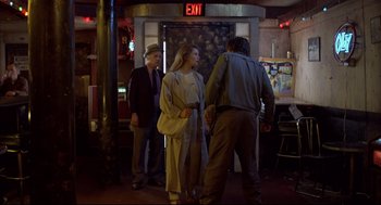 Movie still from “Barfly” (1987), directed by Barbet Schroeder – A group of people standing in front of an exit sign; Wide shot, Over the shoulder angle