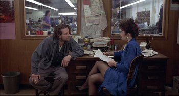 Movie still from “Barfly” (1987), directed by Barbet Schroeder – A man and a woman sitting at a desk; Medium shot, Over the shoulder angle