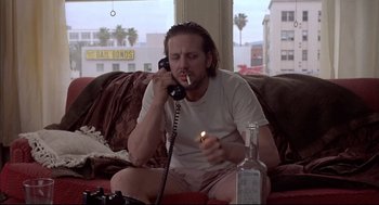 Movie still from “Barfly” (1987), directed by Barbet Schroeder – A man sitting on a couch talking on the phone; Medium shot, Low angle
