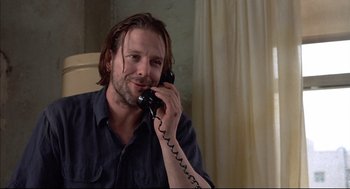 Movie still from “Barfly” (1987), directed by Barbet Schroeder – A man talking on a phone while sitting in a room; Close Up shot, Low angle