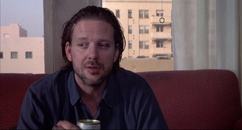 Movie still from “Barfly” (1987), directed by Barbet Schroeder – A person sitting on a couch holding a cup; Close Up shot, Low angle
