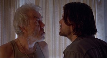 Movie still from “Barfly” (1987), directed by Barbet Schroeder – Two men face each other in front of a window; Close Up shot, Low angle