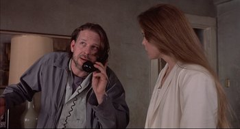 Movie still from “Barfly” (1987), directed by Barbet Schroeder – A man talking on a phone next to a woman; Close Up shot, Low angle