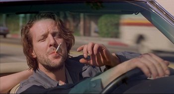 Movie still from “Barfly” (1987), directed by Barbet Schroeder – A man smoking a cigarette while driving a car; Close Up shot, Low angle