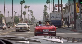 Movie still from “Barfly” (1987), directed by Barbet Schroeder – Two people in the back seat of a red convertible car; Wide shot, High angle