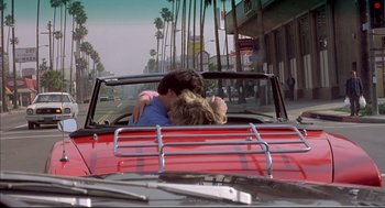 Movie still from “Barfly” (1987), directed by Barbet Schroeder – Two people kissing in the back seat of a red car; Wide shot, High angle