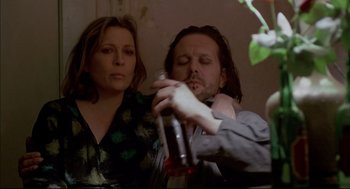 Movie still from “Barfly” (1987), directed by Barbet Schroeder – A man and a woman are holding a bottle of alcohol; Close Up shot, Low angle