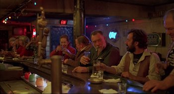 Movie still from “Barfly” (1987), directed by Barbet Schroeder – A group of people sitting at a bar drinking and smoking; Medium shot, Over the shoulder angle