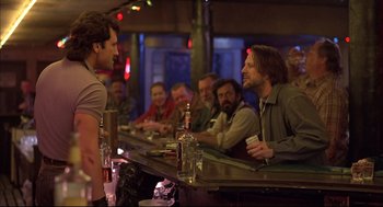 Movie still from “Barfly” (1987), directed by Barbet Schroeder – A group of people sitting at a bar with drinks; Medium shot, Over the shoulder angle