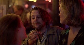 Movie still from “Barfly” (1987), directed by Barbet Schroeder – A man with long hair is smoking a cigarette while a woman looks on; Close Up shot, Low angle