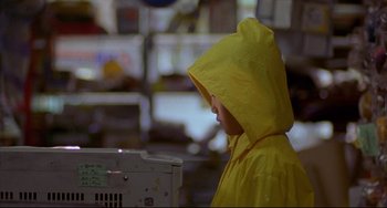 Movie still from “Barking Dogs Never Bite” (2000), directed by Bong Joon Ho – A person wearing a yellow raincoat in a room; Close Up shot, Over the shoulder angle