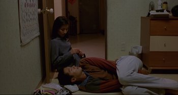 Movie still from “Barking Dogs Never Bite” (2000), directed by Bong Joon Ho – A man and a woman laying on the floor; Wide shot, High angle
