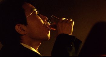 Movie still from “Barking Dogs Never Bite” (2000), directed by Bong Joon Ho – A man in a suit drinking a glass of wine; Extreme Close Up shot, Low angle
