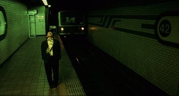 Movie still from “Barking Dogs Never Bite” (2000), directed by Bong Joon Ho – A man in a suit standing next to a train; Wide shot, Low angle