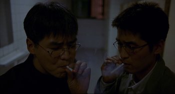 Movie still from “Barking Dogs Never Bite” (2000), directed by Bong Joon Ho – A couple of people that are sitting down smoking; Close Up shot, High angle