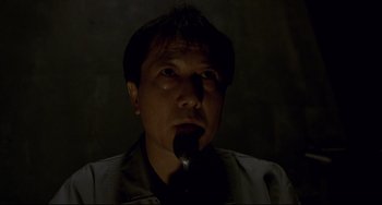 Movie still from “Barking Dogs Never Bite” (2000), directed by Bong Joon Ho – A man is holding a spoon in his mouth; Close Up shot, Low angle