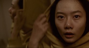Movie still from “Barking Dogs Never Bite” (2000), directed by Bong Joon Ho – A young asian woman is hiding under a blanket; Extreme Close Up shot, Low angle