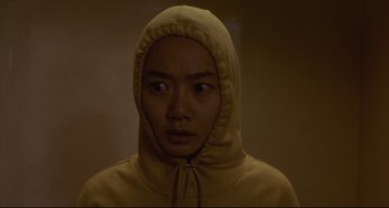 Movie still from “Barking Dogs Never Bite” (2000), directed by Bong Joon Ho – A person wearing a hooded sweatshirt looking at the camera; Close Up shot, High angle