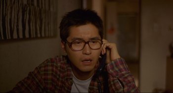 Movie still from “Barking Dogs Never Bite” (2000), directed by Bong Joon Ho – A man with glasses talking on a phone; Close Up shot, High angle