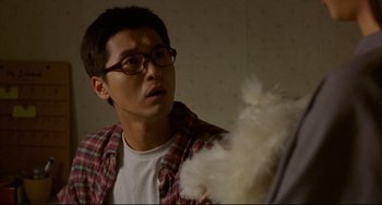 Movie still from “Barking Dogs Never Bite” (2000), directed by Bong Joon Ho – A man holding a feather duster in his hand; Close Up shot, Over the shoulder angle