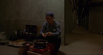 Movie still from “Barking Dogs Never Bite” (2000), directed by Bong Joon Ho – A man sitting in front of a pot on a stove; Medium shot, High angle