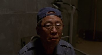 Movie still from “Barking Dogs Never Bite” (2000), directed by Bong Joon Ho – An older man wearing glasses and a hat; Close Up shot, High angle