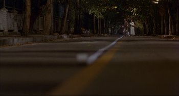 Movie still from “Barking Dogs Never Bite” (2000), directed by Bong Joon Ho – A couple of people standing on the side of a road; Extreme Wide shot, High angle