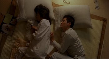 Movie still from “Barking Dogs Never Bite” (2000), directed by Bong Joon Ho – A man and a woman sitting on a bed with a dog; Wide shot, Overhead angle