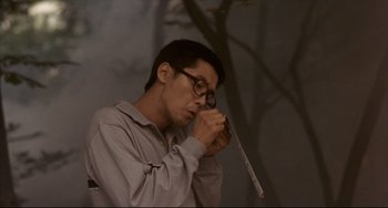 Movie still from “Barking Dogs Never Bite” (2000), directed by Bong Joon Ho – A man with glasses is holding something in his hand; Medium shot, Low angle