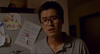 Movie still from “Barking Dogs Never Bite” (2000), directed by Bong Joon Ho – A man wearing glasses and a white polo shirt; Close Up shot, Low angle