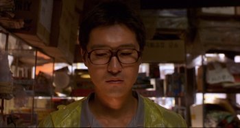Movie still from “Barking Dogs Never Bite” (2000), directed by Bong Joon Ho – A man wearing glasses and a yellow jacket; Close Up shot, Low angle