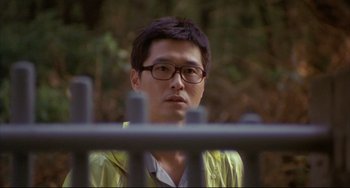 Movie still from “Barking Dogs Never Bite” (2000), directed by Bong Joon Ho – A man wearing glasses and a yellow shirt; Close Up shot, Over the shoulder angle